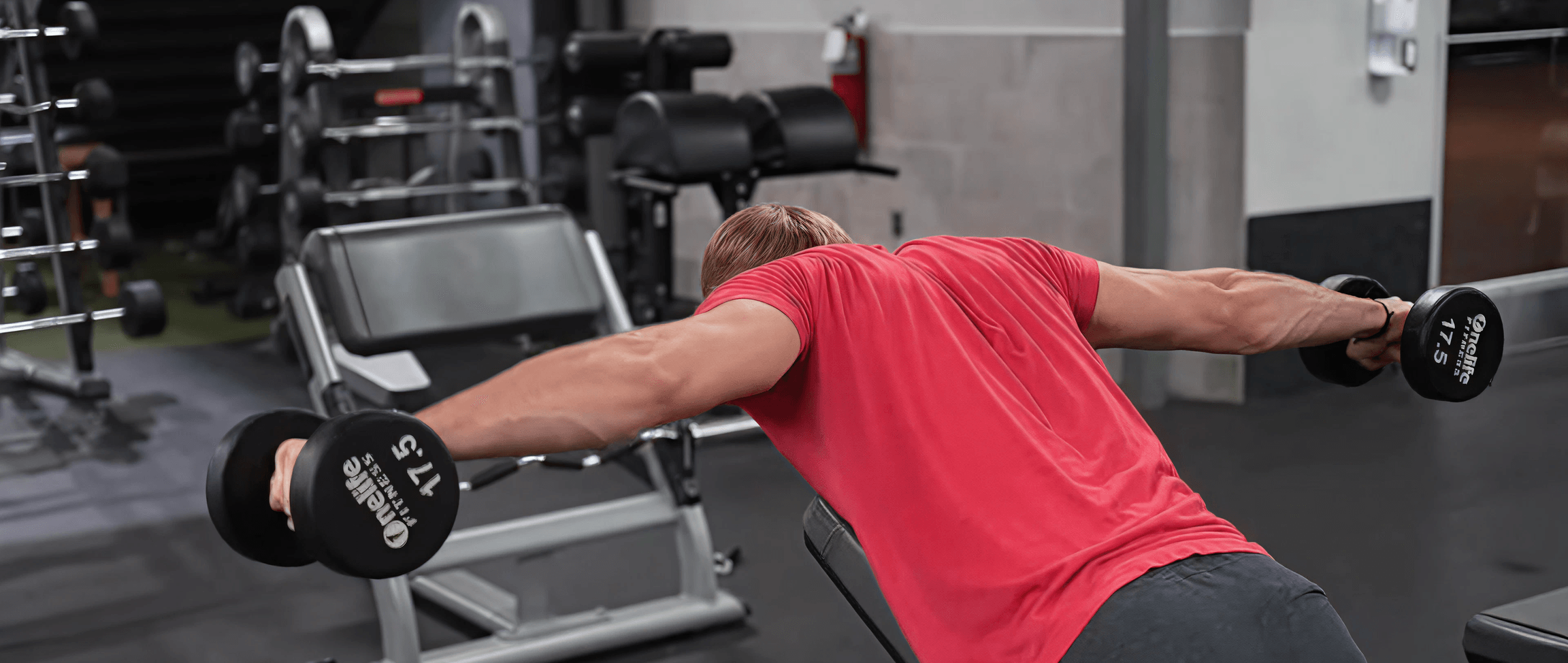 Sam from B4 Fitness showing dumbbell rear delt fly's in a gym
