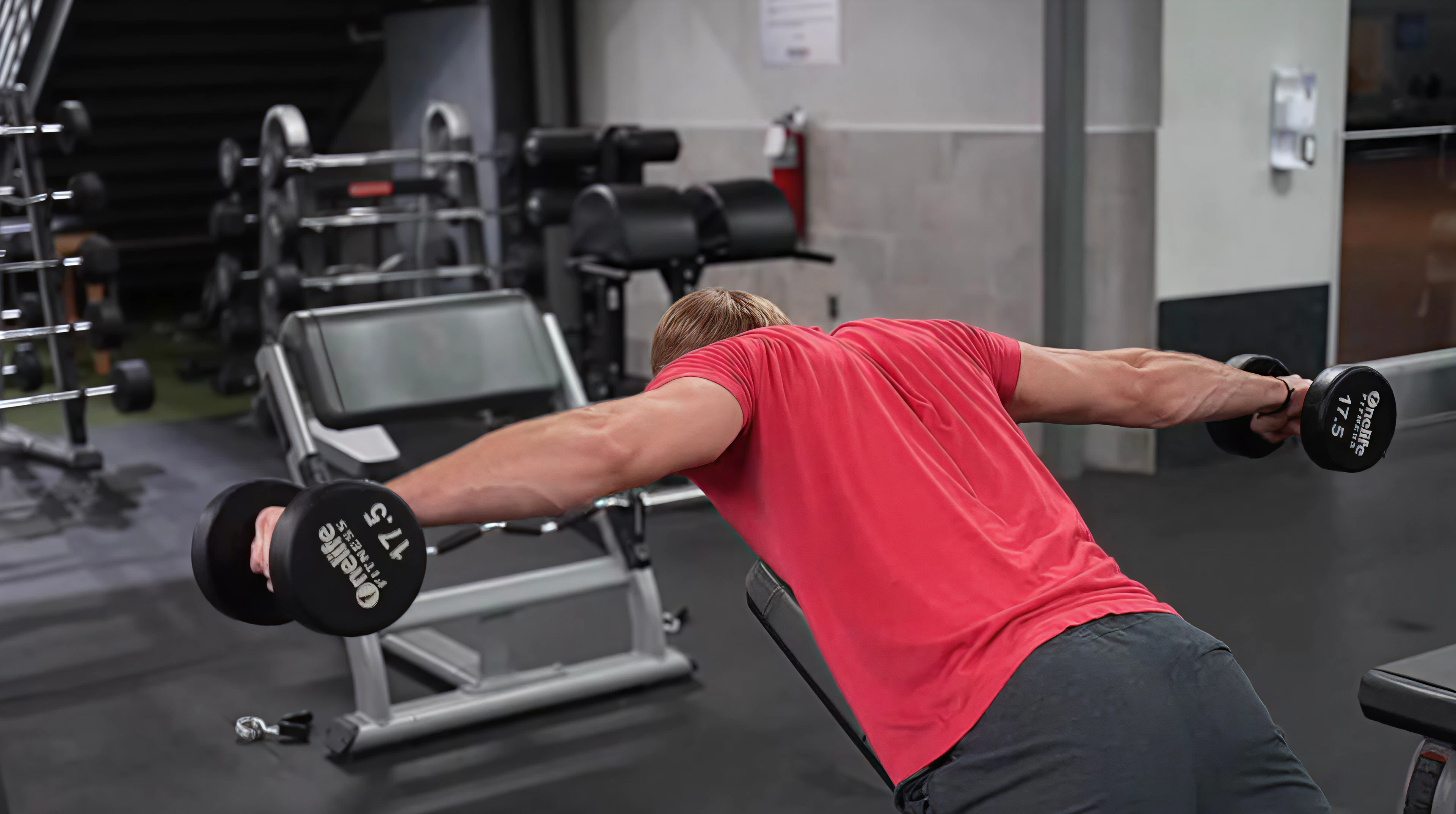 Sam from B4 Fitness showing dumbbell rear delt fly's in a gym